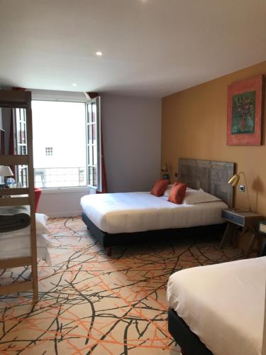 a bedroom with two beds and a large window at Le Prieuré de Boulogne in Tour-en-Sologne
