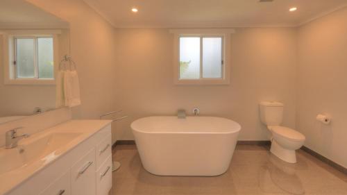 a white bathroom with a tub and a toilet at Castaway Cottage in Dover