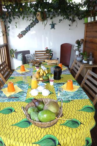 a table with a bowl of fruit on a yellow table cloth at La case o'gecko974 in Saint-Joseph