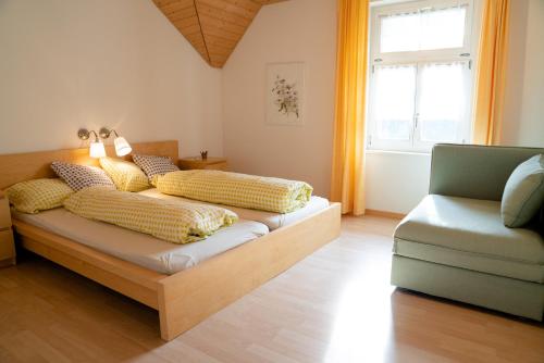 Un dormitorio con una cama con almohadas amarillas y una silla en Ferienwohnung Napf-Chäsi, en Luthern