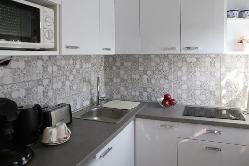 a kitchen with white cabinets and a sink at Aliz Apartman in Miskolc