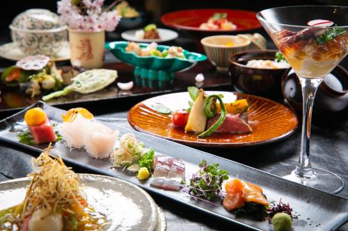 una mesa con platos de comida y una copa de vino en Oyado Den Rikyu en Yufuin