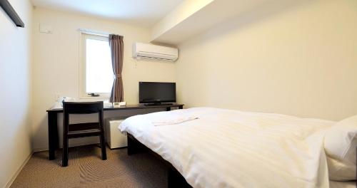 1 dormitorio con 1 cama y escritorio con TV en Value The Hotel Higashi Matsushima Yamoto en Higashimatsushima