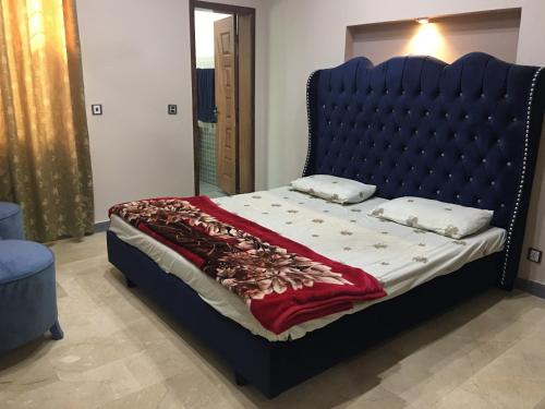 a bed with a blue headboard in a room at Spacious Apartment in Johar Town in Lahore