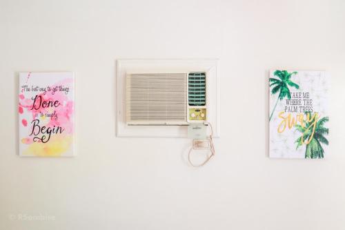 a window in a white wall with two pictures at RQS Hostel in Tacloban
