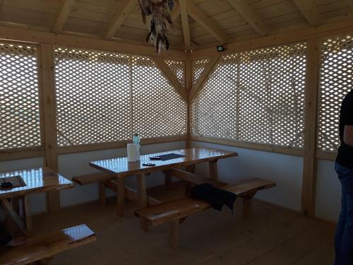 um quarto com mesas e bancos de madeira num quarto com janelas em Apartments in Nature em Visoko