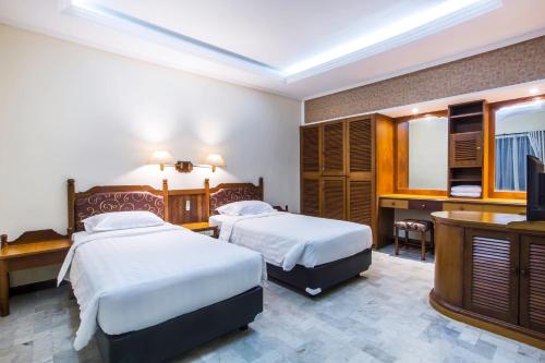 Una habitación de hotel con dos camas y un televisor. en Bali Bungalo Hotel, en Kuta