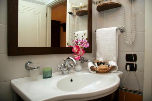 un lavandino in bagno con specchio e fiori di Hotel U' Bais a Scilla