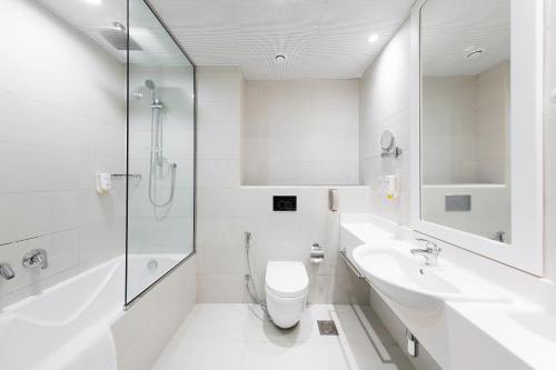 a white bathroom with a toilet and a sink at Citymax Hotel Al Barsha in Dubai