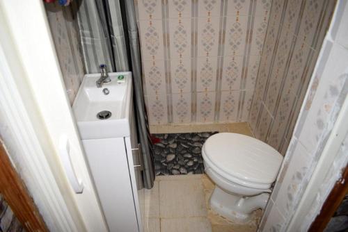 a small bathroom with a toilet and a sink at Sasana Motel and Guest House in Bungoma