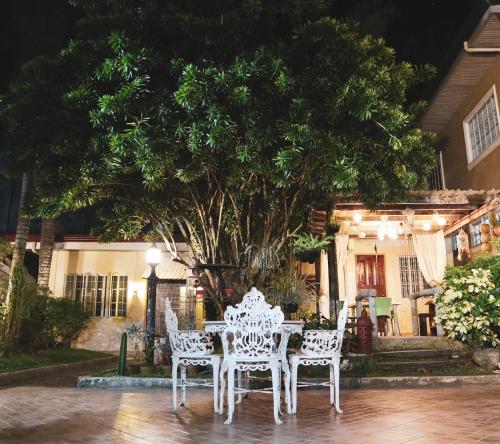 a white table and chairs in front of a tree at RQS Hostel in Tacloban
