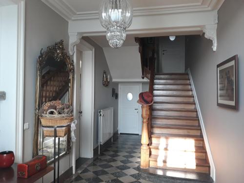 a hallway with a staircase and a chandelier at Les Glaneuses in Mettet