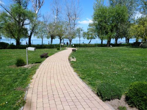 a brick path in a park with a bench at Sunrise Apartman in Siófok