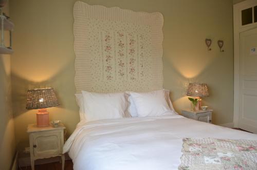 een slaapkamer met een wit bed en 2 lampen bij Les Glaneuses in Mettet