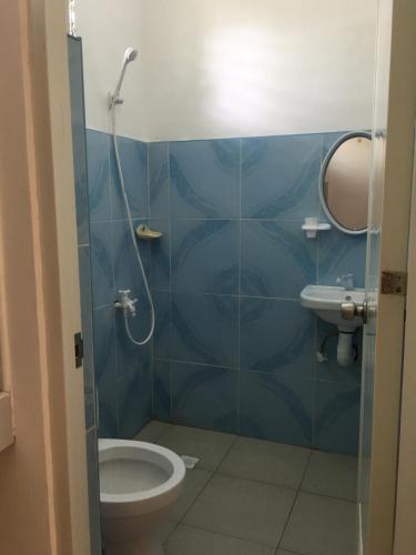 a blue tiled bathroom with a toilet and a sink at Panglao Rainbow Inn in Tagbilaran City