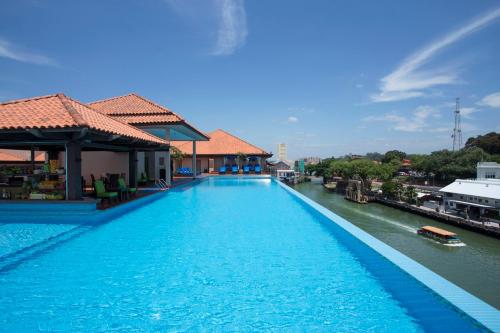 a large swimming pool next to a river at Casa del Rio Melaka in Melaka