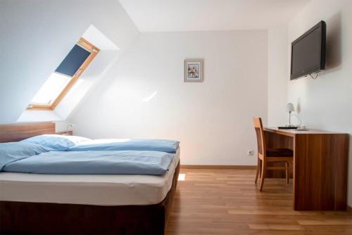 Dormitorio con cama, escritorio y TV en Hotel Seewind, en Norddeich