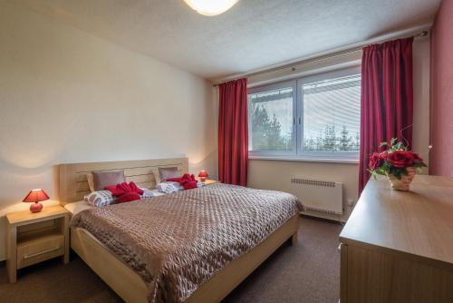 a bedroom with a bed with red curtains and a window at Classy Apartment - Ski Telgart in Telgárt