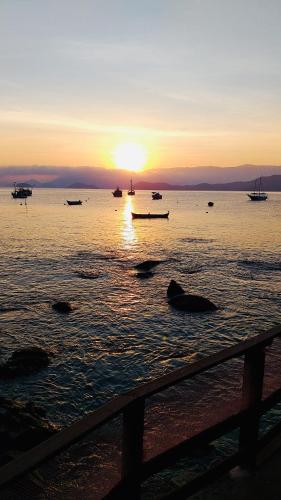 a sunset over a body of water with boats at Pousada Sobre As Ondas de Picinguaba in Picinguaba