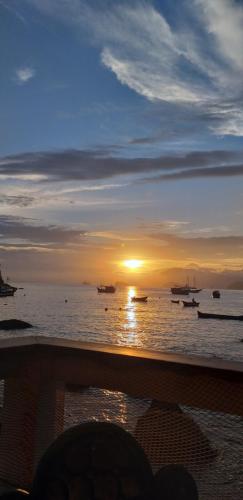 a sunset on the beach with boats in the water at Pousada Sobre As Ondas de Picinguaba in Picinguaba