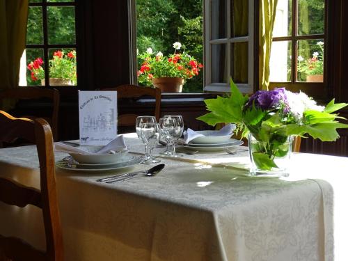 une table avec un chiffon de table blanc et des fleurs sur elle dans l'établissement Château de la Redortière, à Lézignac-Durand