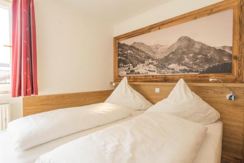 ein Bett mit weißen Kissen und einem Bild an der Wand in der Unterkunft Oberstdorfer Bergwelt 213 in Oberstdorf