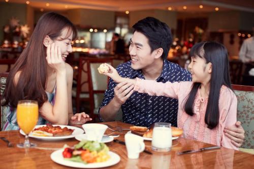 a man and two girls sitting at a table eating food at Fairmont Yangcheng Lake in Kunshan