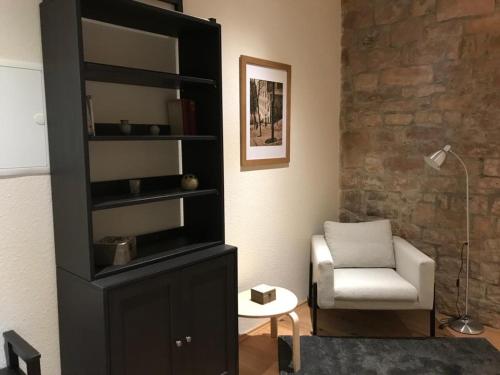 a living room with a black book shelf and a chair at Gästehaus Windheim (Ettlingen) in Ettlingen