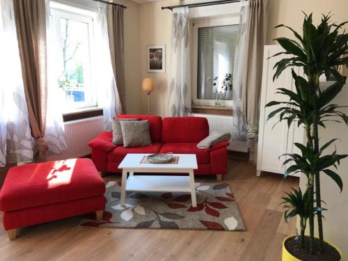 a living room with a red couch and a table at Gästehaus Windheim (Ettlingen) in Ettlingen