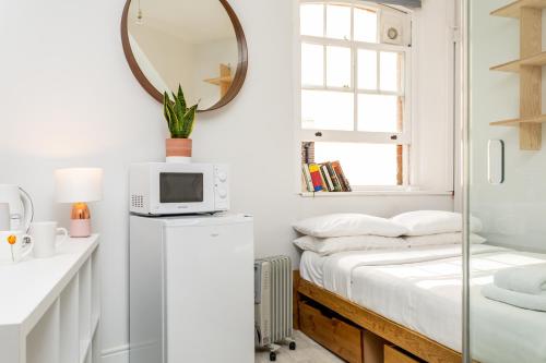 a white bedroom with a bed and a mirror at Beautiful pied-a-terre to explore London in London