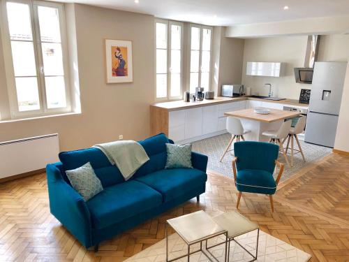 a living room with a blue couch and a kitchen at Le 57 by Sparnapart in Épernay