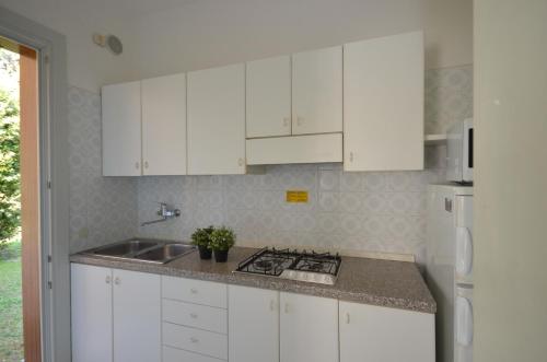a white kitchen with white cabinets and a sink at Ville Dogi Sud in Bibione