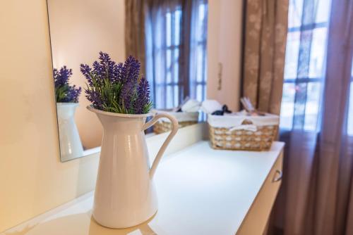 a white vase with purple flowers in it on a counter at Anastasia House in Panagia