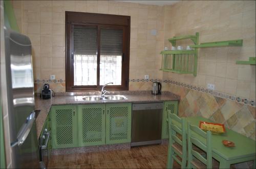 eine grüne Küche mit einem Waschbecken und einem Fenster in der Unterkunft Casa MamaTere in Benamahoma