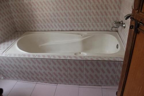 a white bath tub in a room with a tile floor at Hotel Vision in Gorkhā
