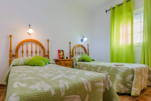 2 camas en un dormitorio con cortinas verdes en Apartamento Calle Alta, en Conil de la Frontera