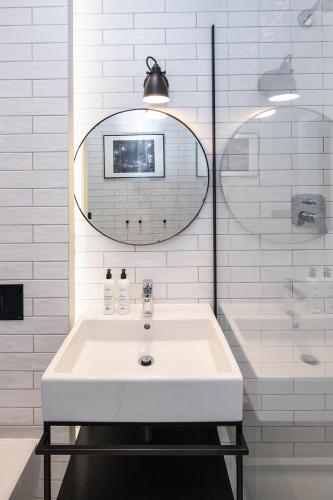 a white bathroom with a sink and a mirror at Apartamenty przy Monte Cassino in Sopot