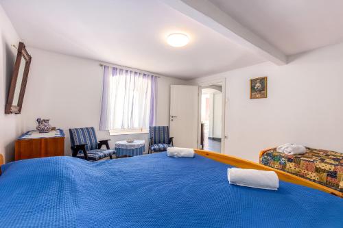 a bedroom with a large blue bed and two chairs at Apartment Lucija in Bakar