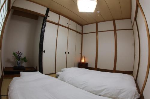 two beds in a room with white walls at Stay Omihachiman Ekimae Inn in Omihachiman