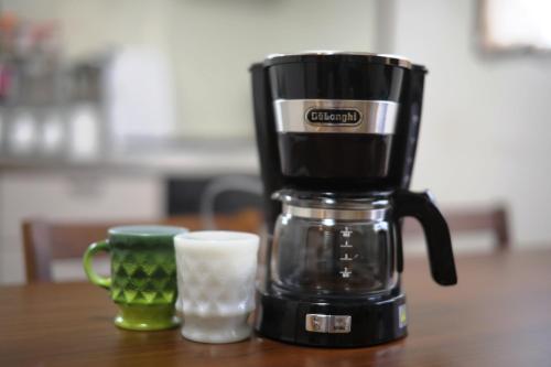 a coffee maker and a cup on a table at Stay Omihachiman Ekimae Inn in Omihachiman