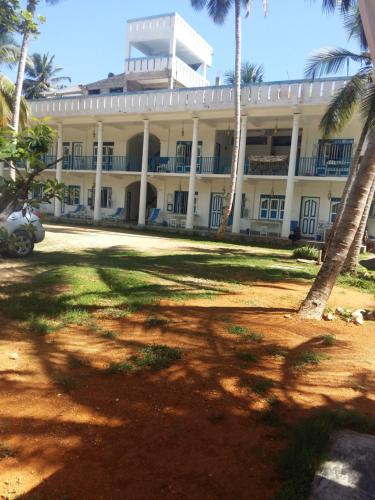 a large building with palm trees in front of it at Zimmer Rest in Unawatuna