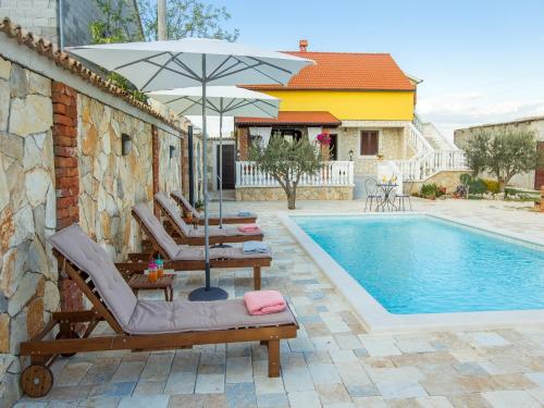 uma piscina com duas espreguiçadeiras e um guarda-sol em Holiday home Iva with pool em Sukošan