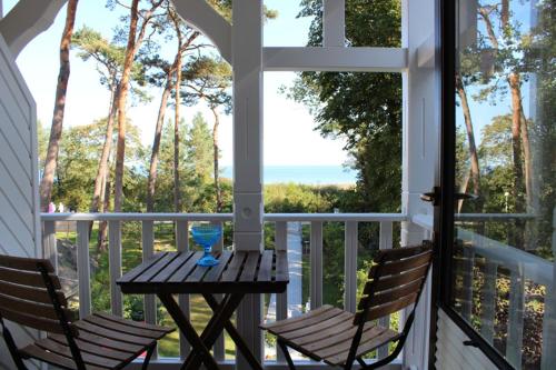 a table and two chairs on a porch with a view of the ocean at Villa Waldheim - WG 1 in Boltenhagen
