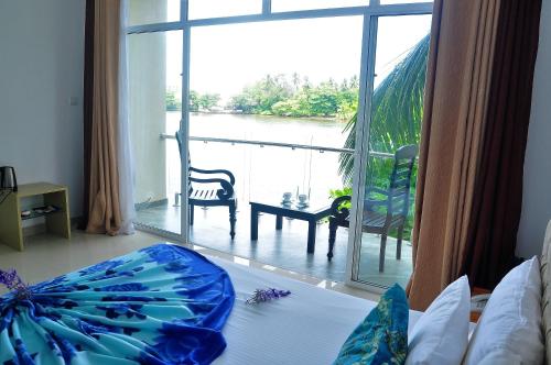 a bedroom with a large window with a view of the water at Amber House Lanka in Bentota
