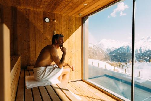 a man sitting in a sauna talking on a cell phone at Hotel Enzian Hochsölden Superior in Sölden