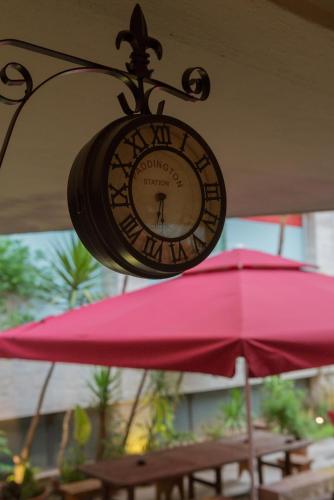 a clock hanging from the ceiling next to a pink umbrella at Mosaic Home in Tirana
