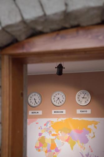 four clocks on a wall with a map of the world at Mosaic Home in Tirana