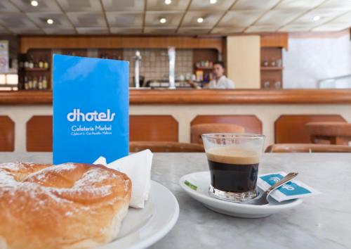 a cup of coffee and a doughnut on a table at Hotel Marbel in Can Pastilla