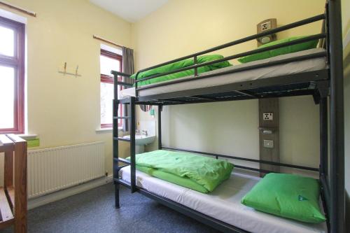 2 Etagenbetten in einem Zimmer mit grünen Kissen in der Unterkunft YHA Snowdon Llanberis in Llanberis