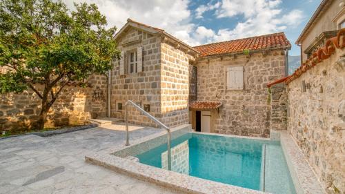 a stone building with a swimming pool in front of it at Beachfront Villa Perast in Perast